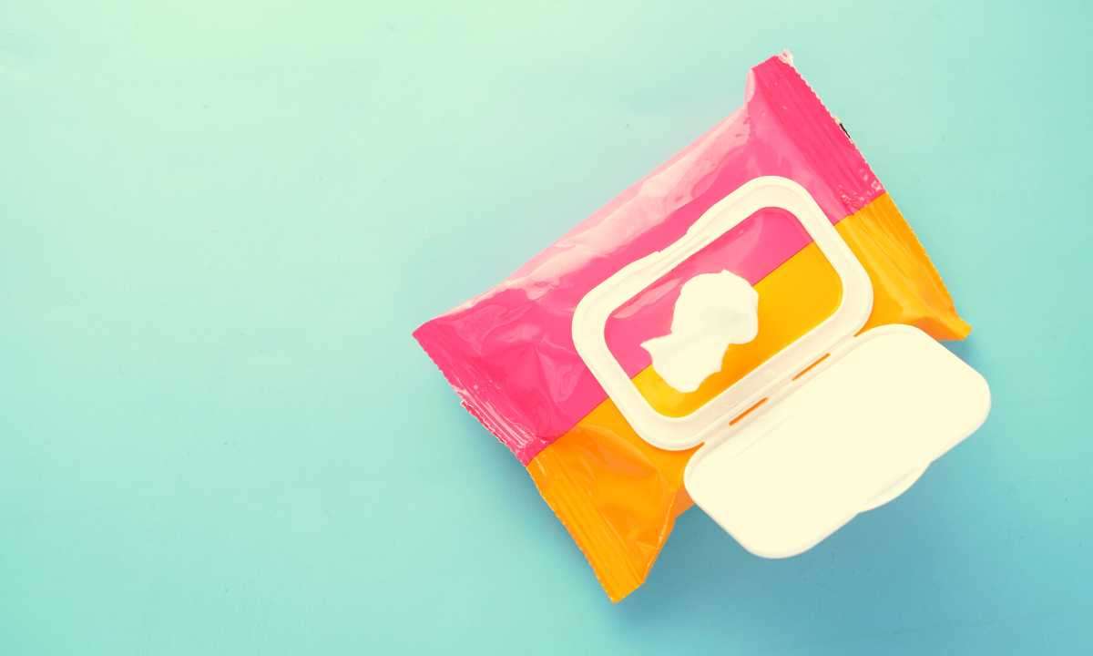An orange and pink bag of baby wipes against a light blue background.
