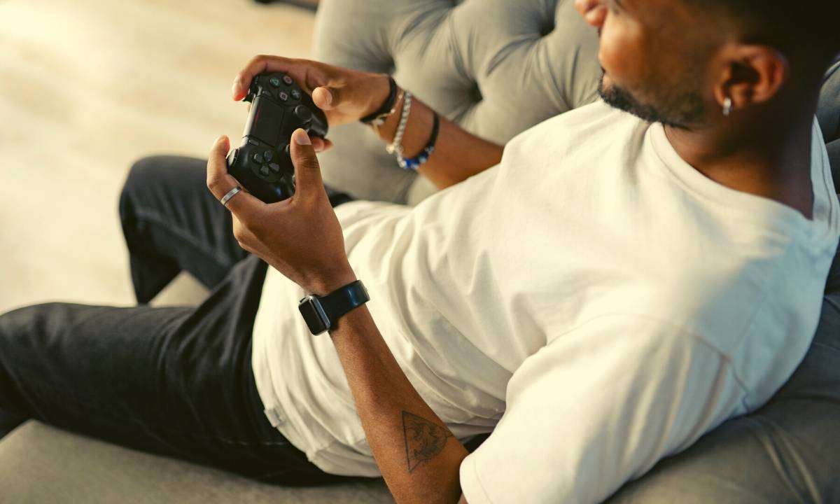 Man gaming comfortably on a sofa.