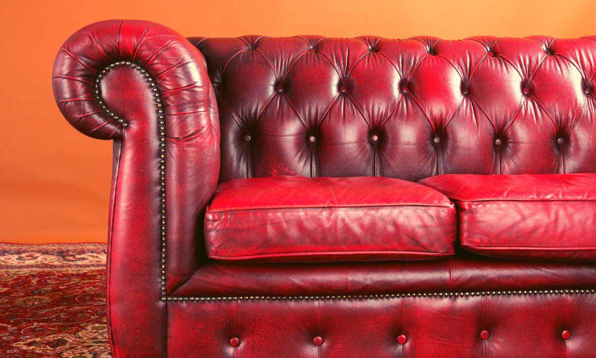A dark red Chesterfield sofa with leather upholstery, deep button tufting, and nailhead trim.