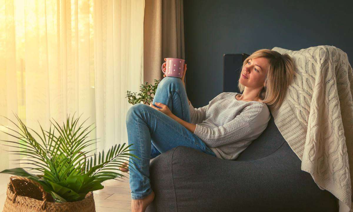 A woman sitting in a bean bag chair with a cup of coffee.