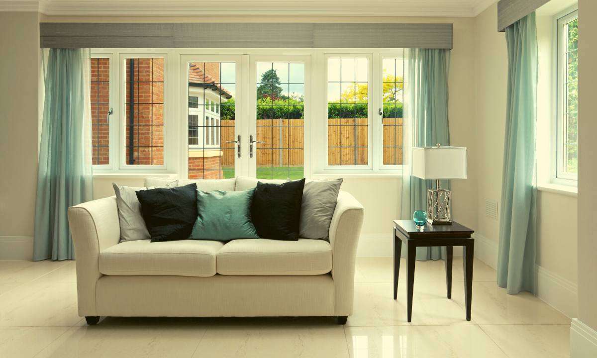 A white settee with throw pillows on it in the middle of a living room.